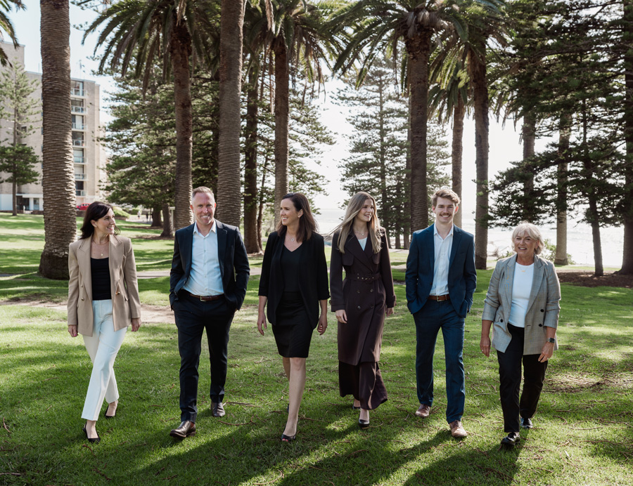 Team of caringbah tax and accounting professionals standing together in a casual, relaxed beachside setting